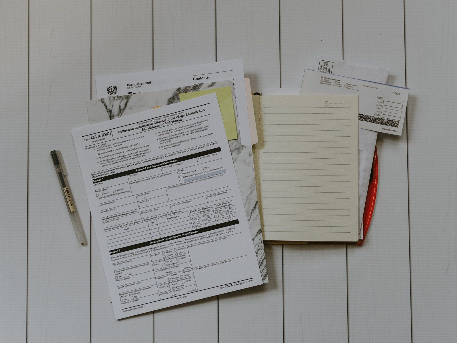 Stack of document forms, a pen and a notebook