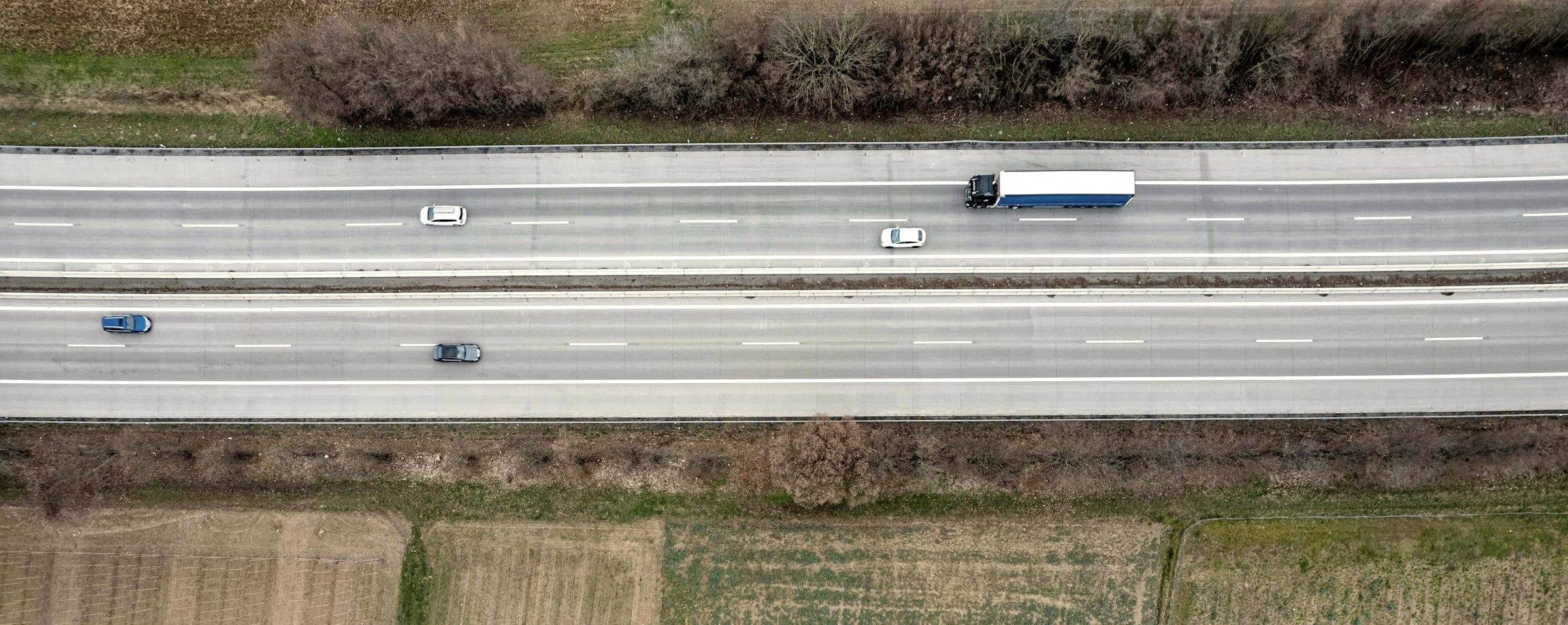 Trucks on a highway through fields, aerial view