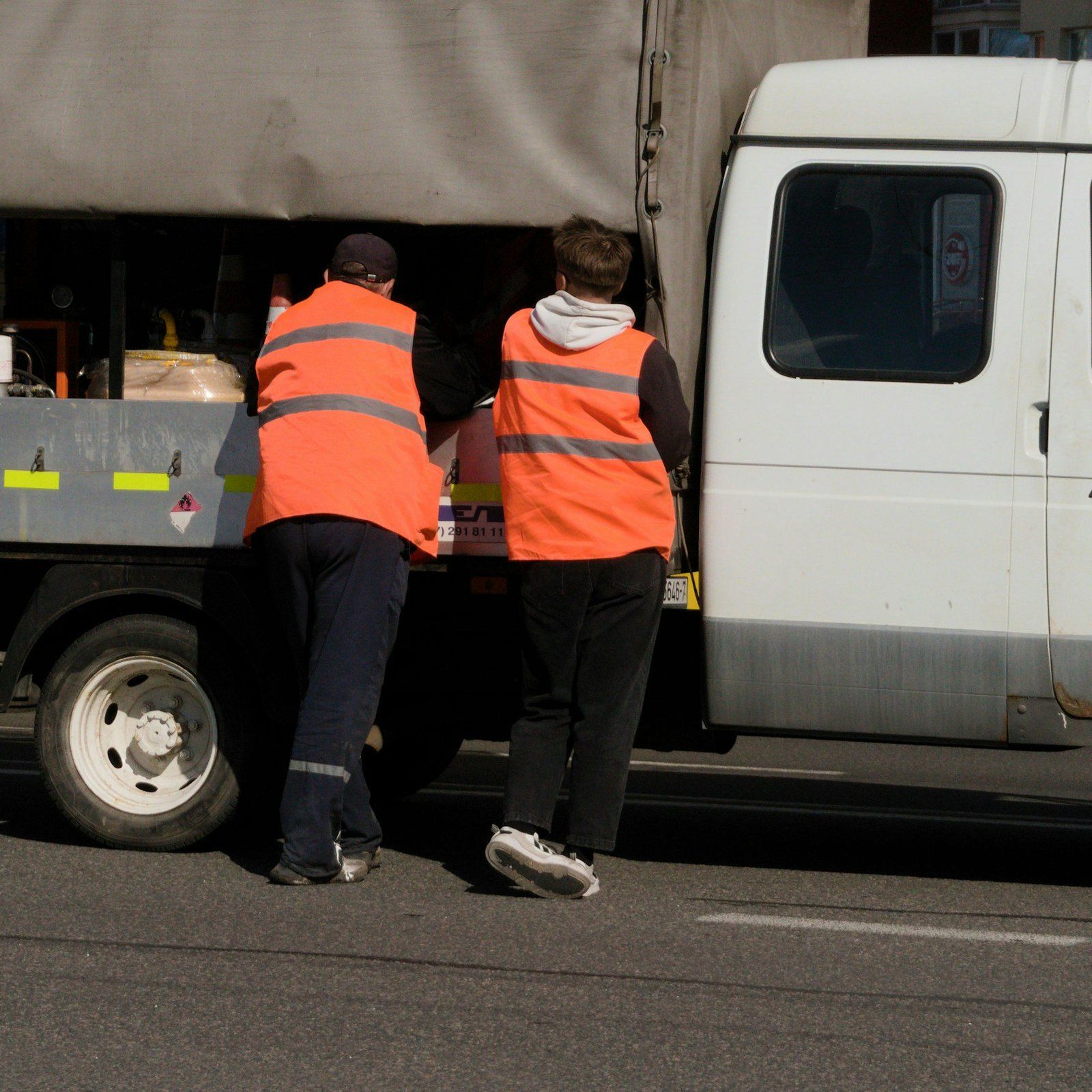 Two workers by a truck on the road