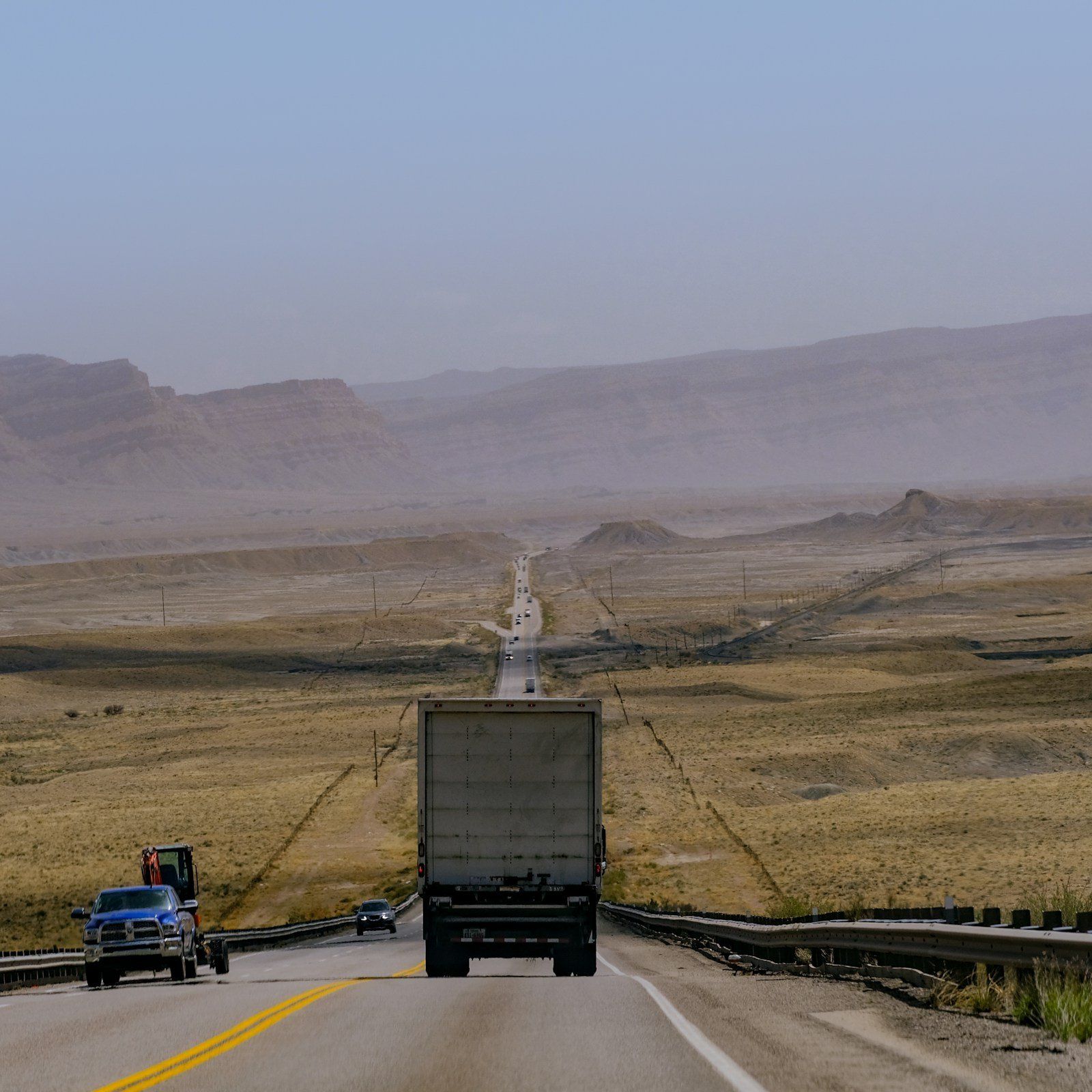 Truck on a long highway through desert mountains